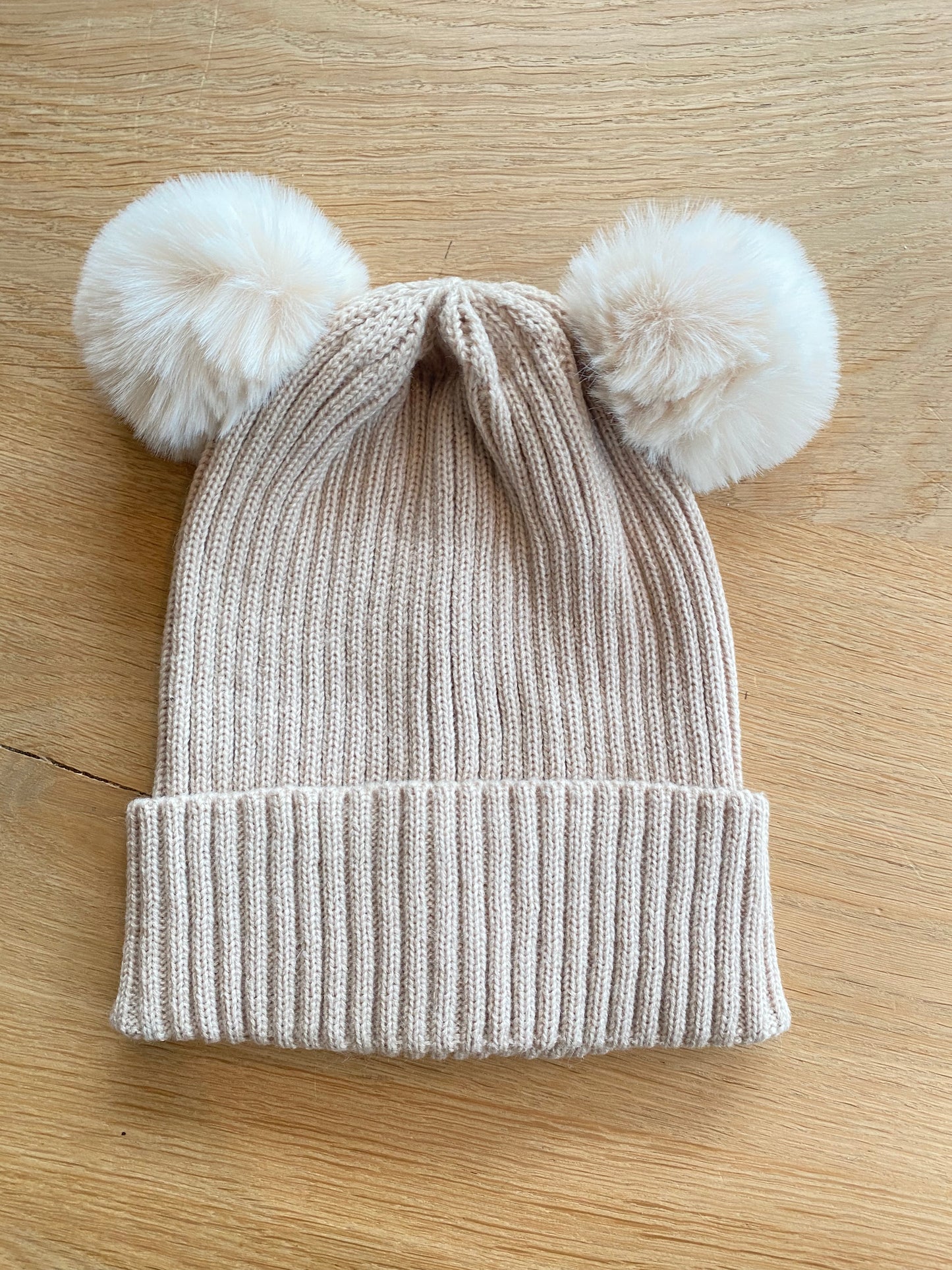 Beige muts met pomponnen