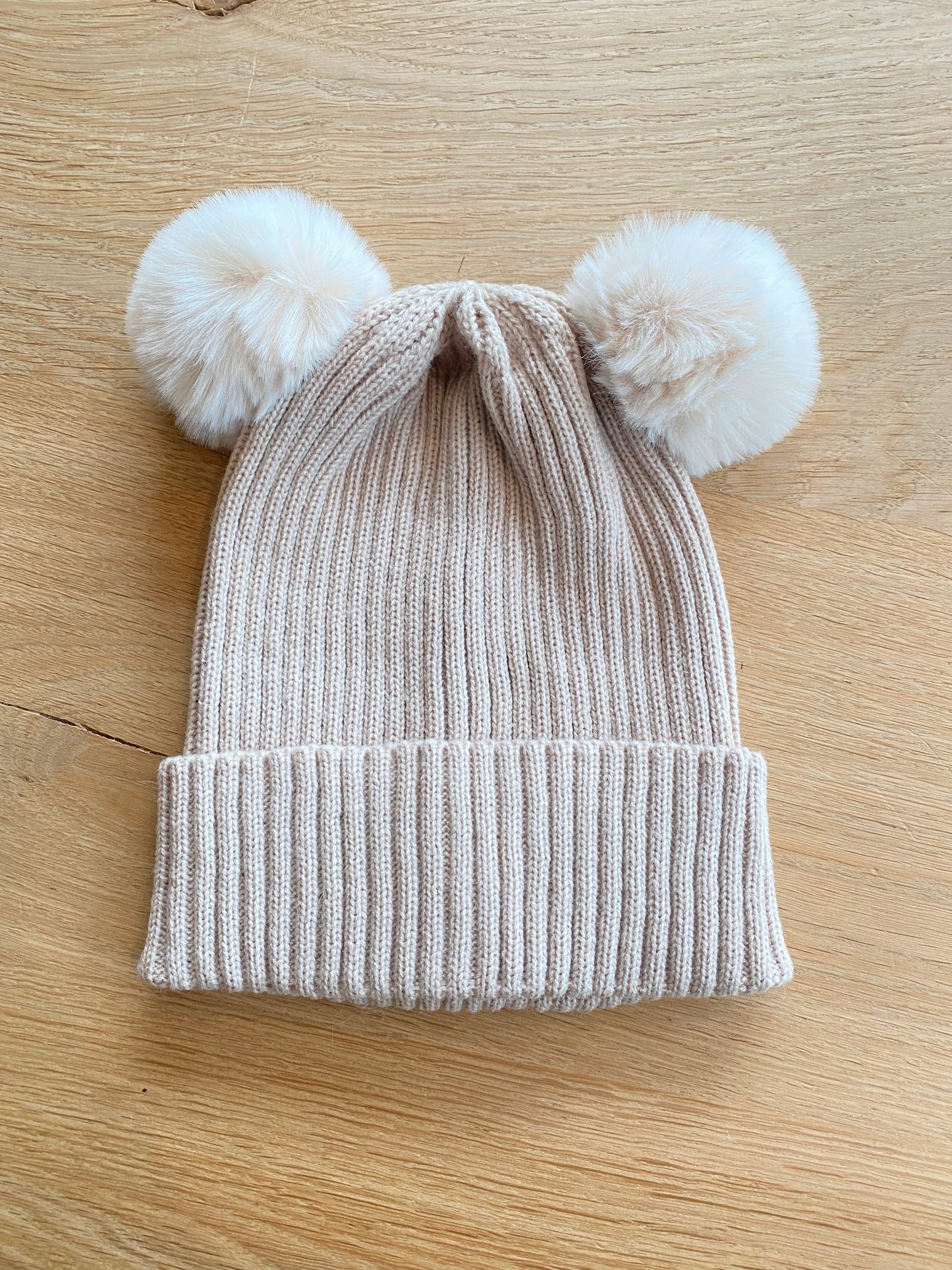 Beige muts met pomponnen