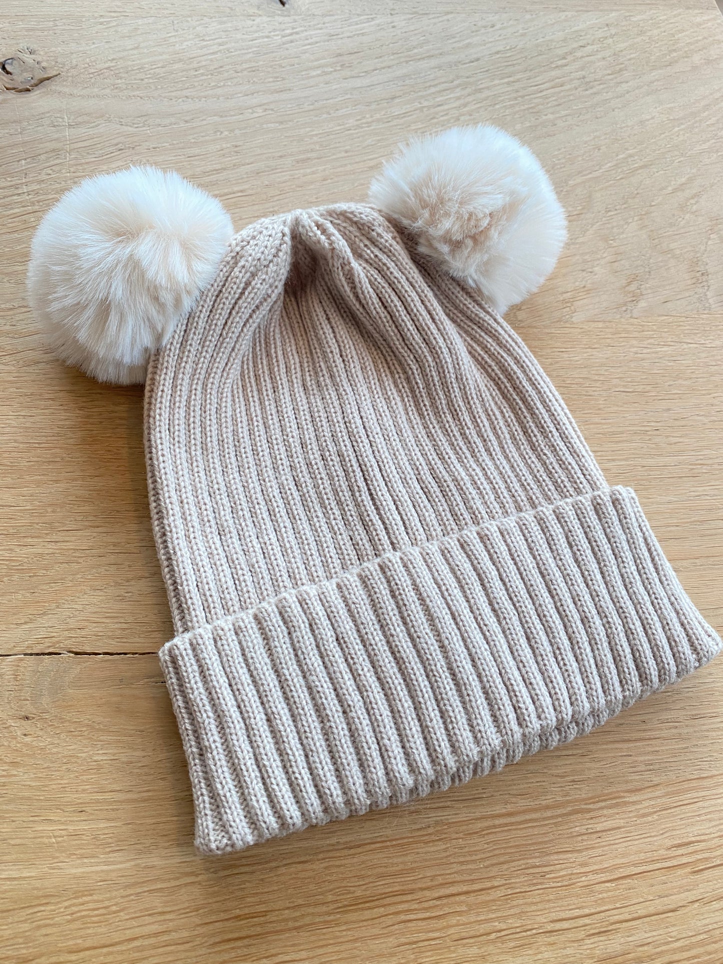 Beige muts met pomponnen