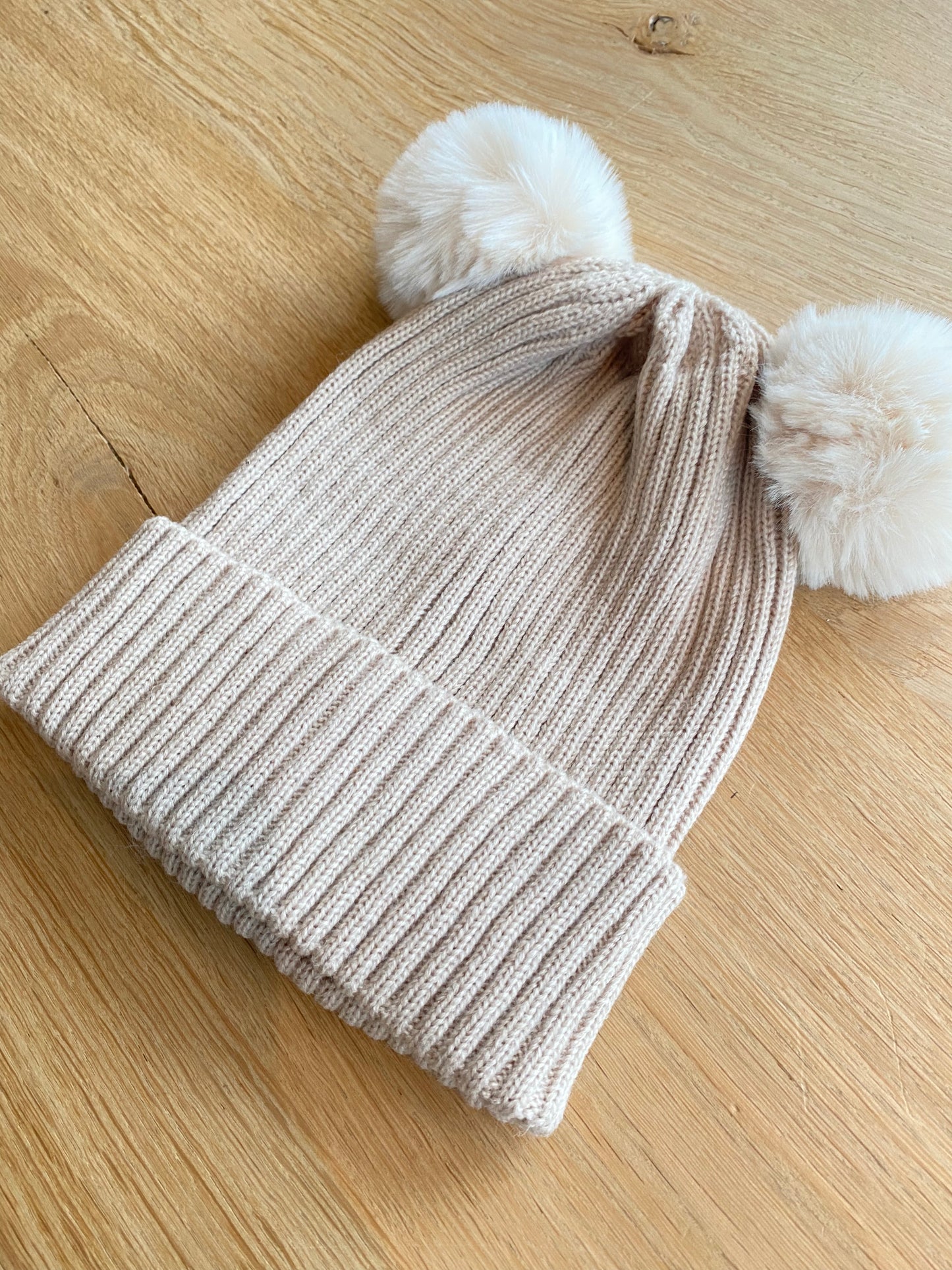 Beige muts met pomponnen